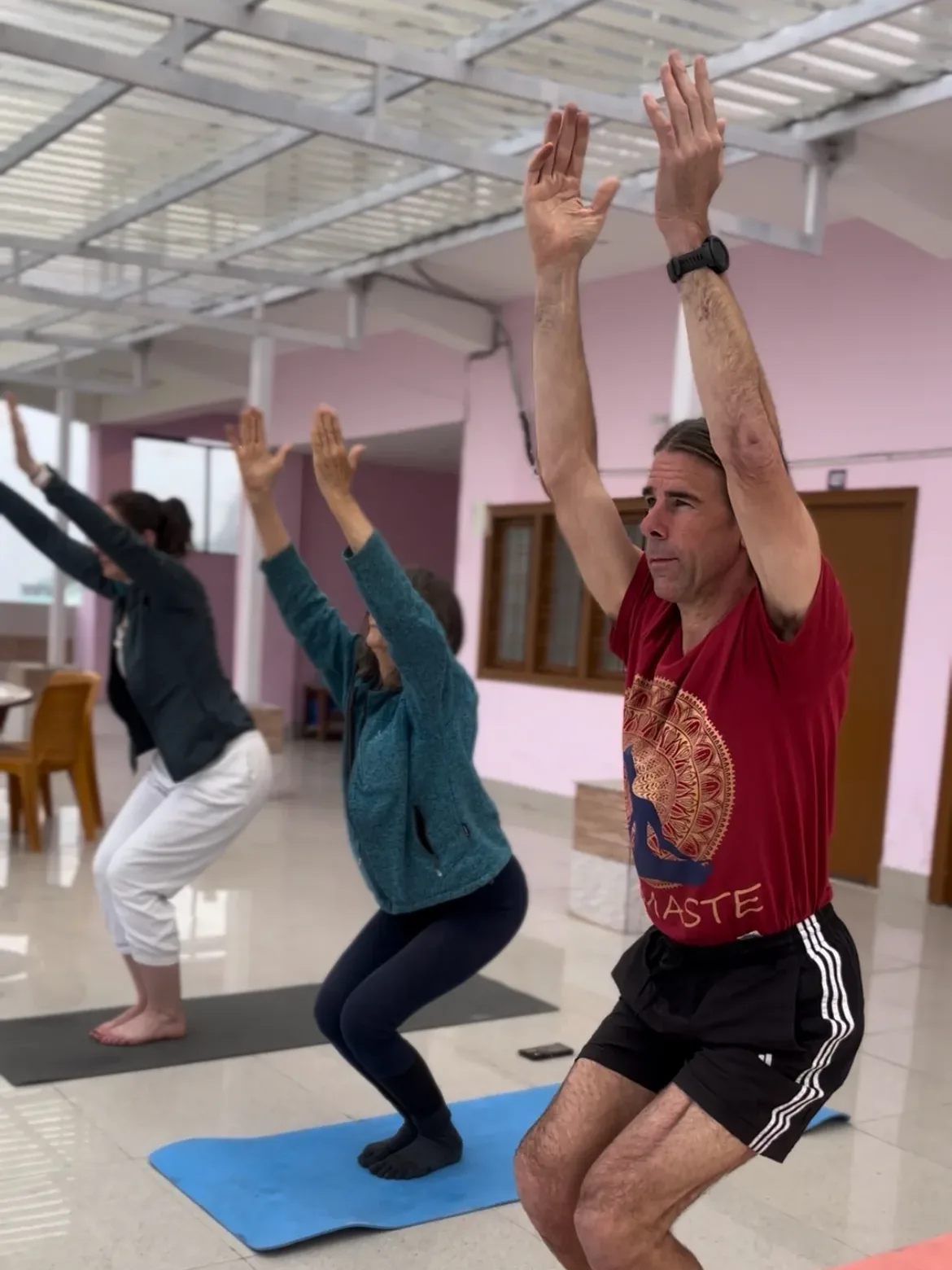 Students practicing Utkatasana chair pose during Yoga Teacher Training course at Adishesh Yoga School in Rishikesh, Uttarakhand, India