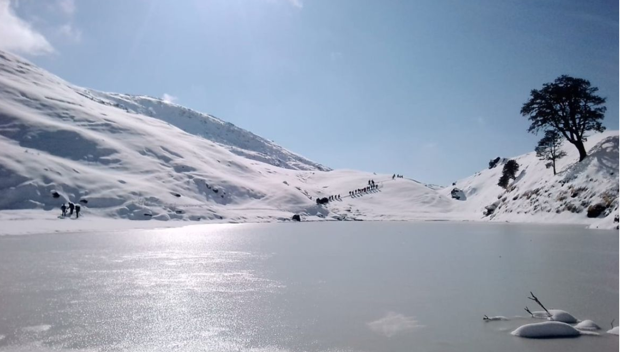 Frozen Brahmatal lake surrounded by snow peaks during winter trek in Uttarakhand