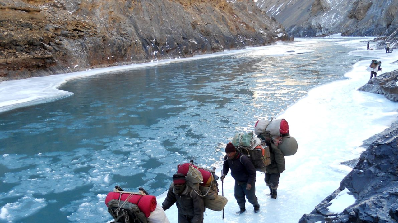 Trekkers walking on the frozen Zanskar River during Chadar Trek in Ladakh winter