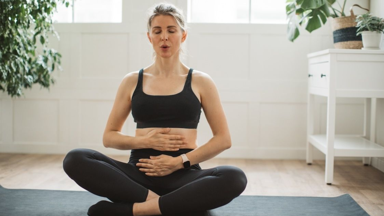 Yoga practitioner demonstrating proper diaphragmatic breathing technique with hands positioned on chest and abdomen