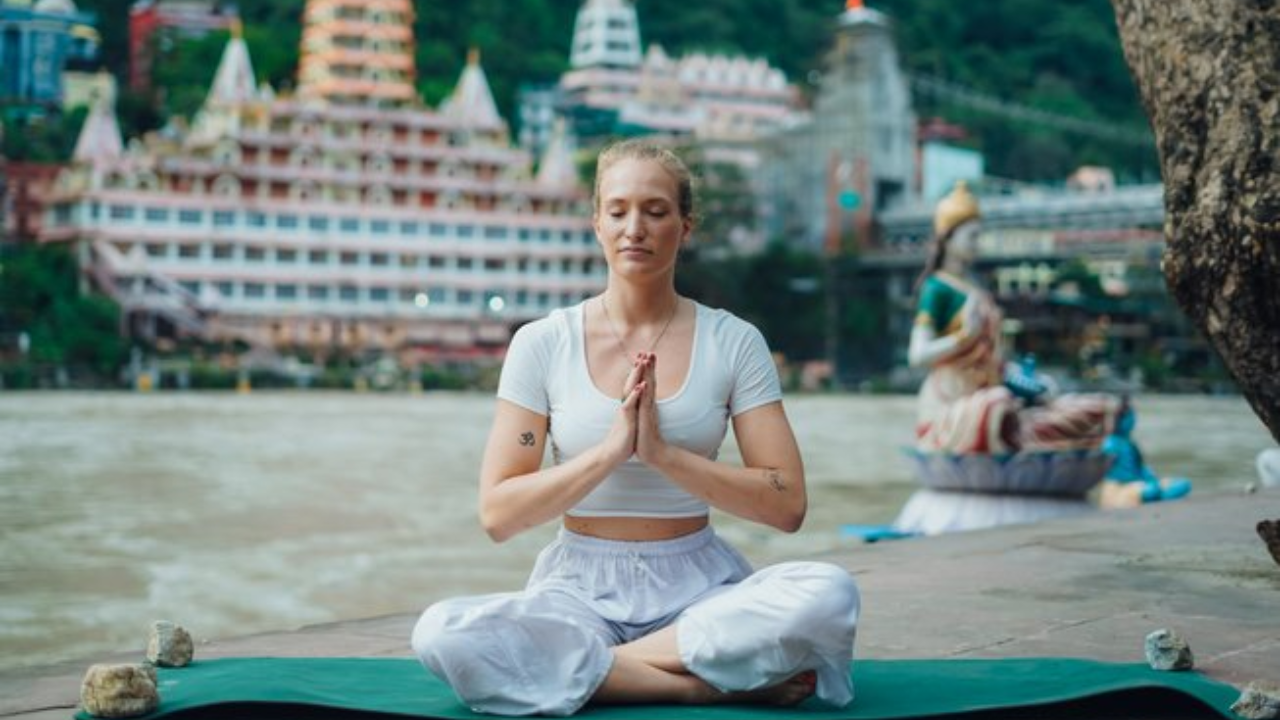 First-time yoga retreat student sitting in morning meditation by the Ganga river in Rishikesh