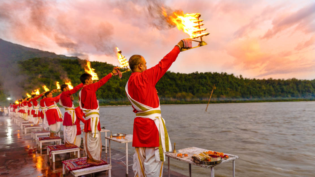Spiritual evening in Rishikesh at sunset with golden Himalayan light reflecting on the holy Ganges river during the sacred prayer ceremony at the ghat