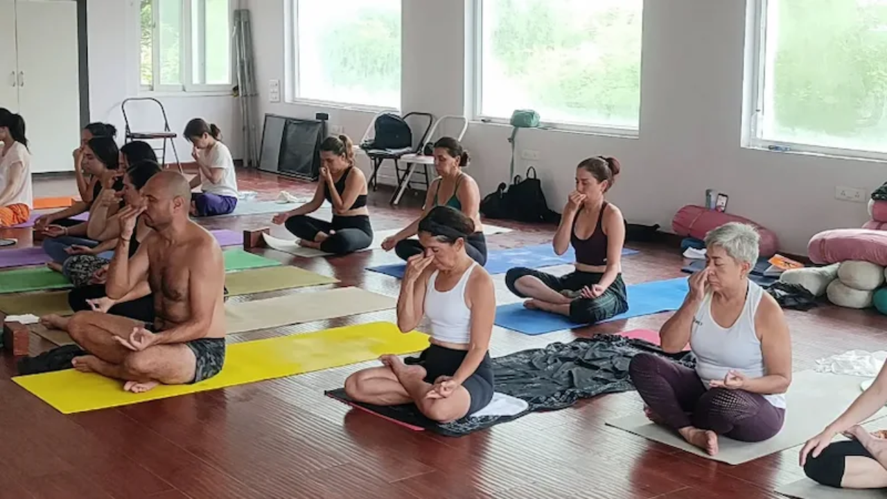 Group yoga class on Rishikesh riverside with Himalayan backdrop and Ganges flow
