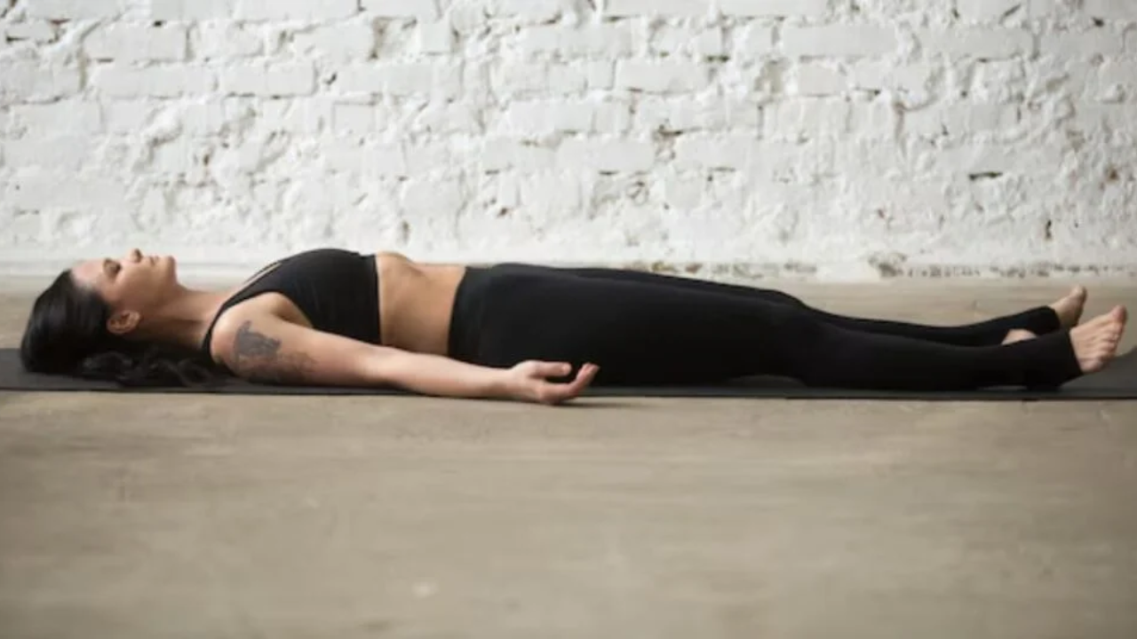 Person practicing Savasana Corpse Pose yoga asana for relaxation and stress relief