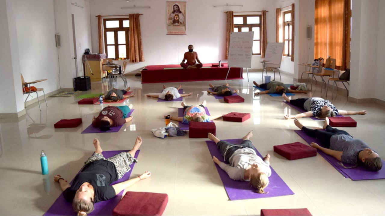 Group of yoga students in Savasana relaxation at the end of a yoga class in Rishikesh shala