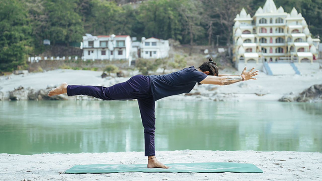 Students practicing Warrior III Pose during morning yoga class at Adishesh Yoga retreat in Rishikesh with Himalayan background