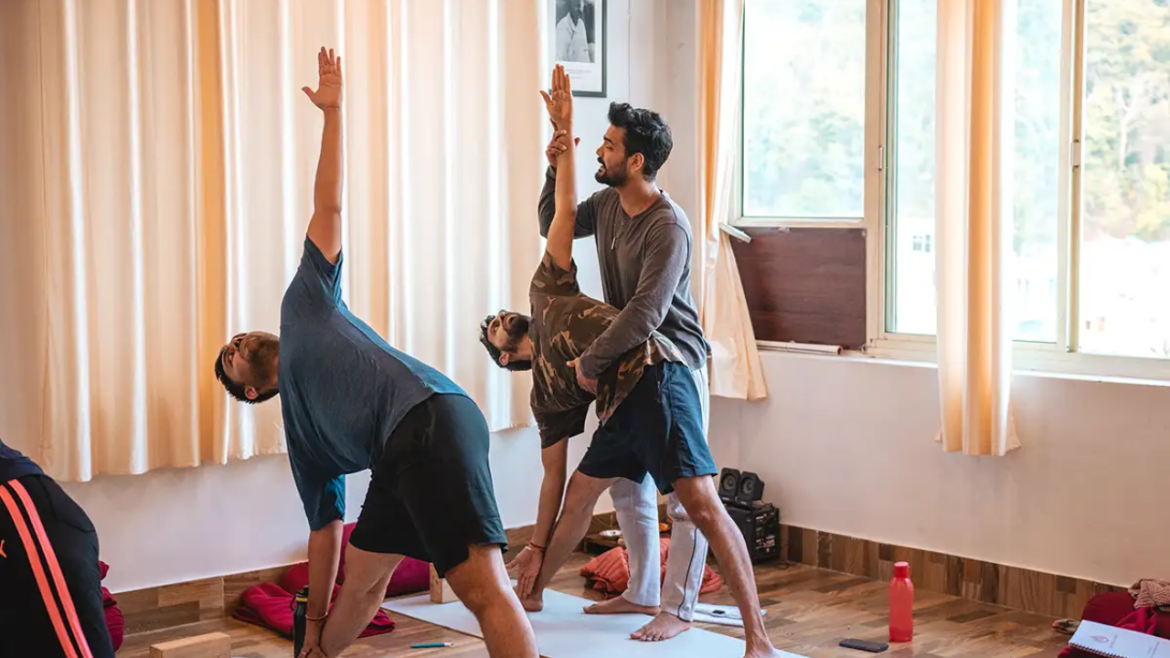 Complete beginner doing first yoga class at retreat in Rishikesh guided by teacher