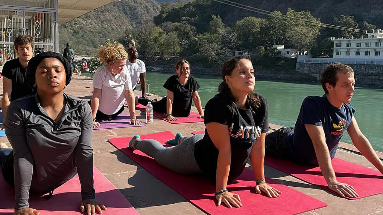 Group of people experiencing the benefits of a yoga retreat — practicing together in an outdoor yoga shala in Rishikesh