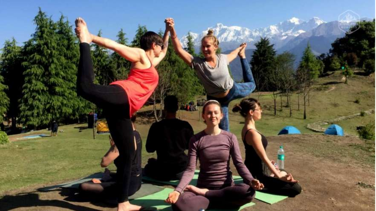 Group of first-time yoga retreat participants doing group practice together in Rishikesh surrounded by mountains